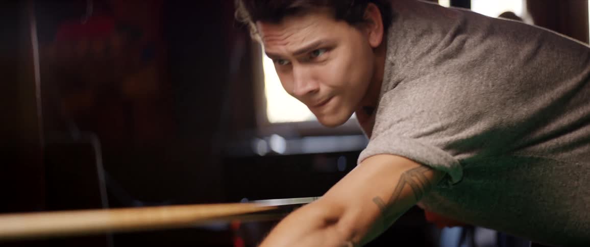 Man playing pool inside of a building with people at a party