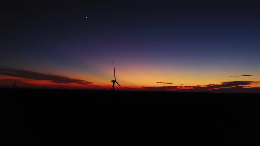 Aerial view of wind turbines rotating in the wind farm at dusk