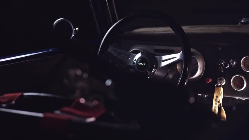A vintage vehicle sits in a dark garage