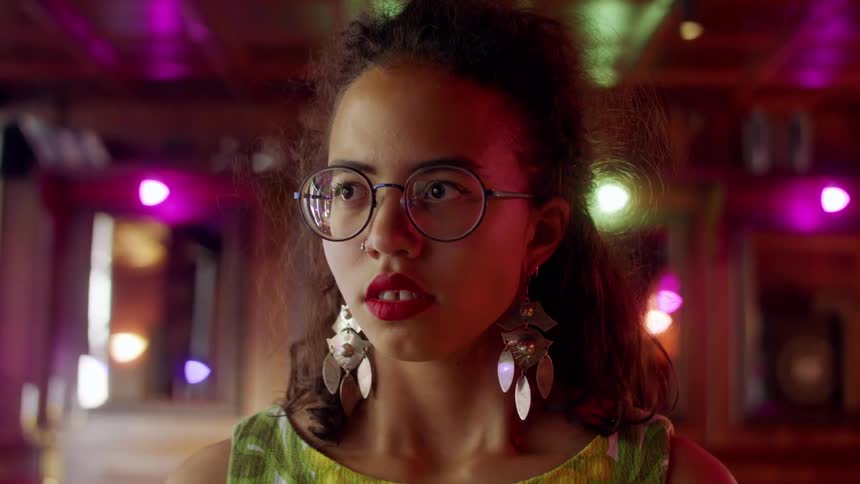 A young girl standing in a room looking ahead and breathing deeply