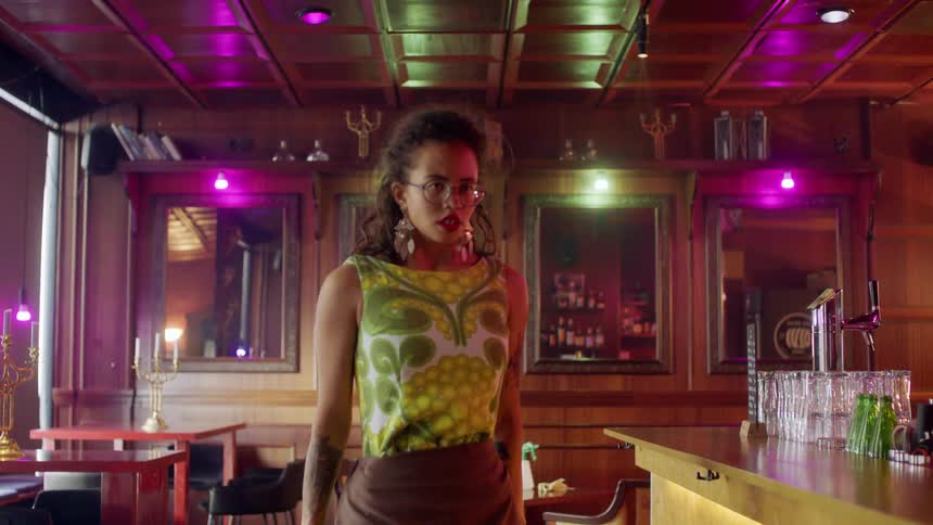 A young girl stands in a bar by herself and takes a deep breath
