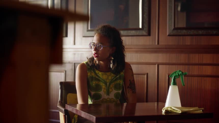 Woman with her head down at a table inside of a restaurant and getting up to look around worryingly