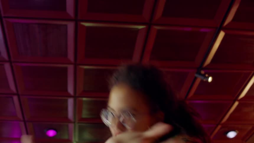 Woman dances under ceiling tinted purple by colored lights
