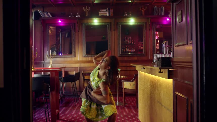 Woman dancing moving her arms and body in a bar at a bar counter by herself