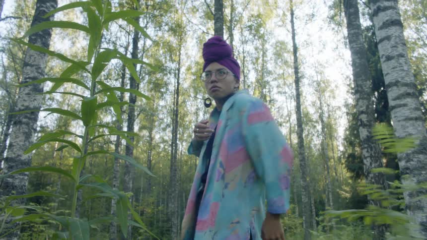 A woman is dancing outdoors in a forest