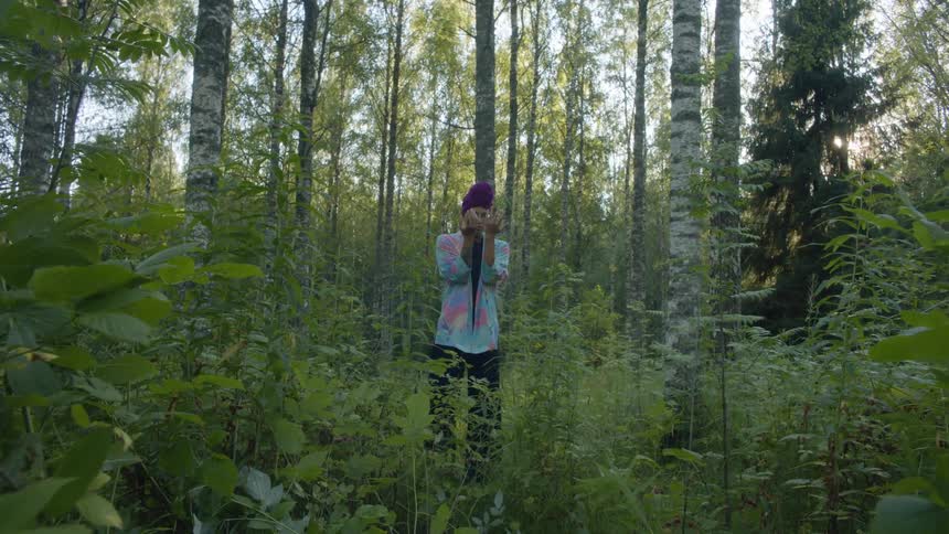 A woman is standing outdoors in the forest
