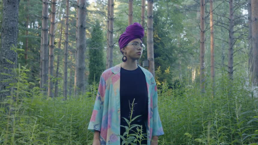 Woman stands in forest clearing looking around searchingly