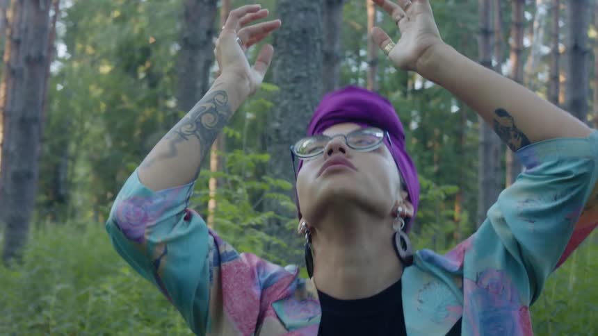 A woman performs modern dance movements in the middle of a forest
