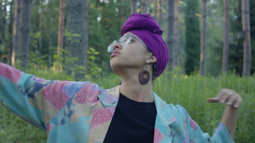 Woman performing dance movements out in a forest