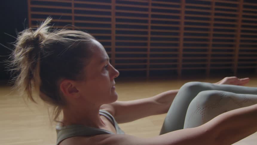 A woman is stretching indoors during the day