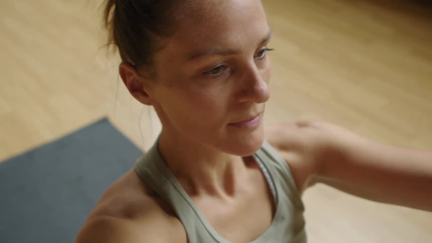 Woman with a ponytail works out on a grey pilates mat in the gym