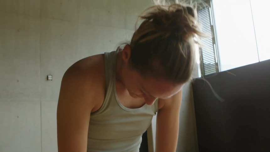 A woman is stretching indoors during the day