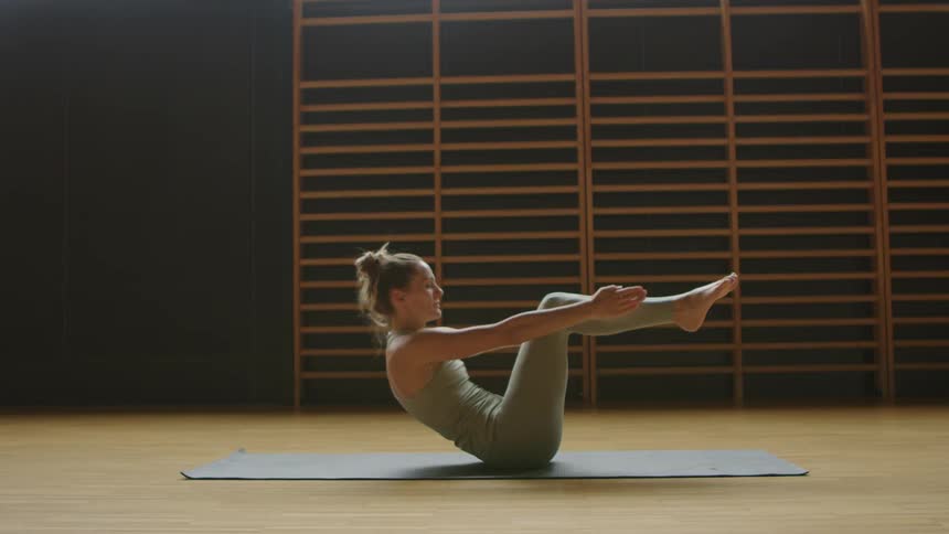I woman is stretching indoors on a floor mat