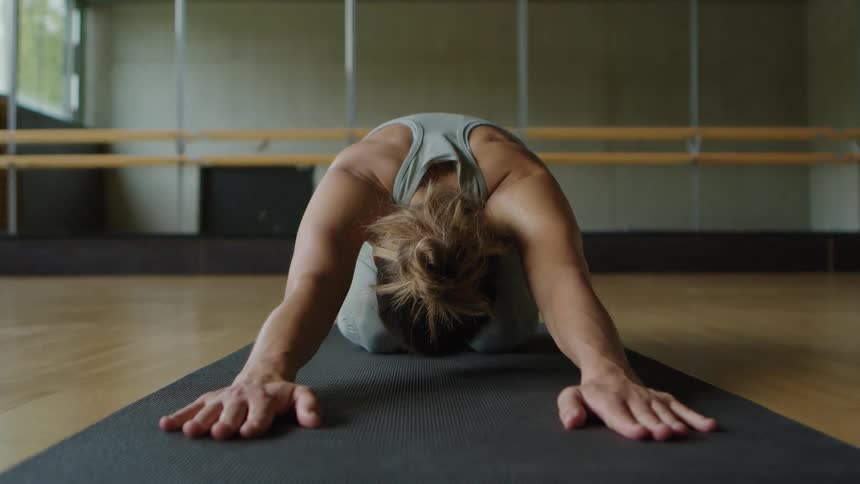 A woman is stretching indoors during the day