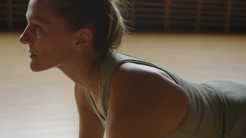 Woman with a grey sport top and leggings does stretches in the gym