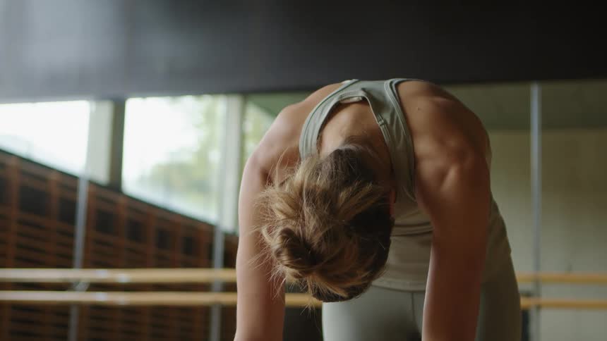 A woman is stretching indoors during the day