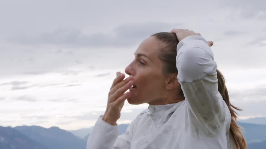 A woman is standing outdoors by a mountain landscape