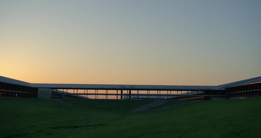 Livestock building on the top of a grassy hill at sunset