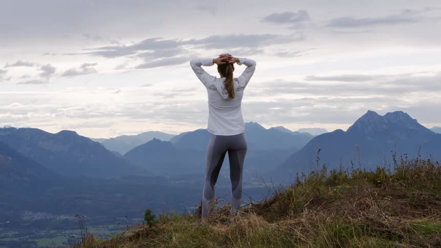 Woman standing at the edge of a mountain top staring off into the distance