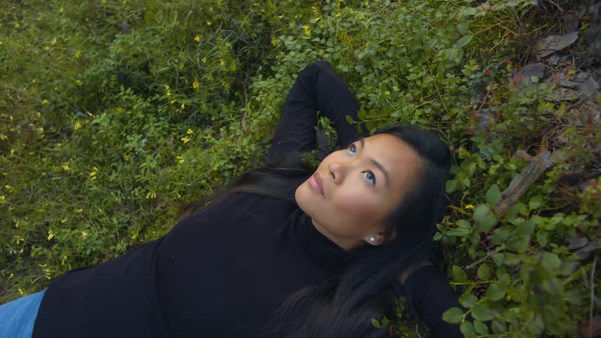 A woman is laying in the grass during the day