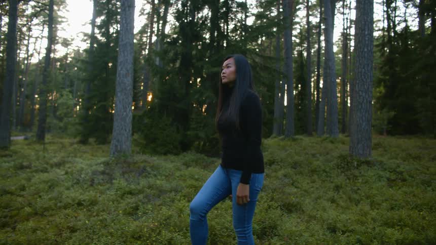 A woman is walking through the woods