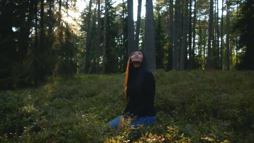 Woman sitting in a grove looking up and around her