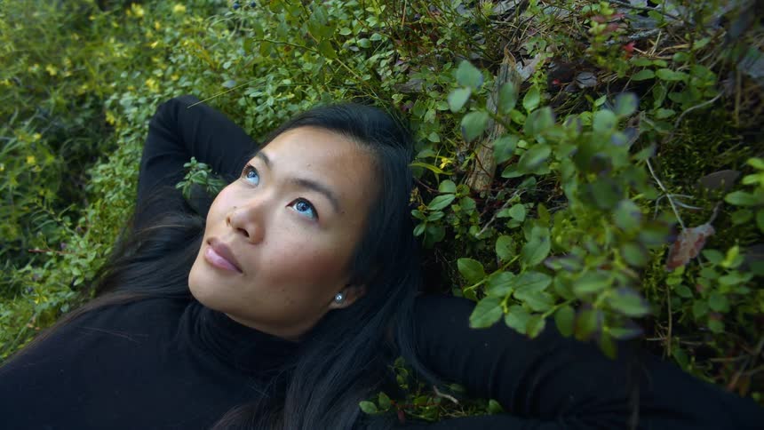 A woman is laying in the grass during the day