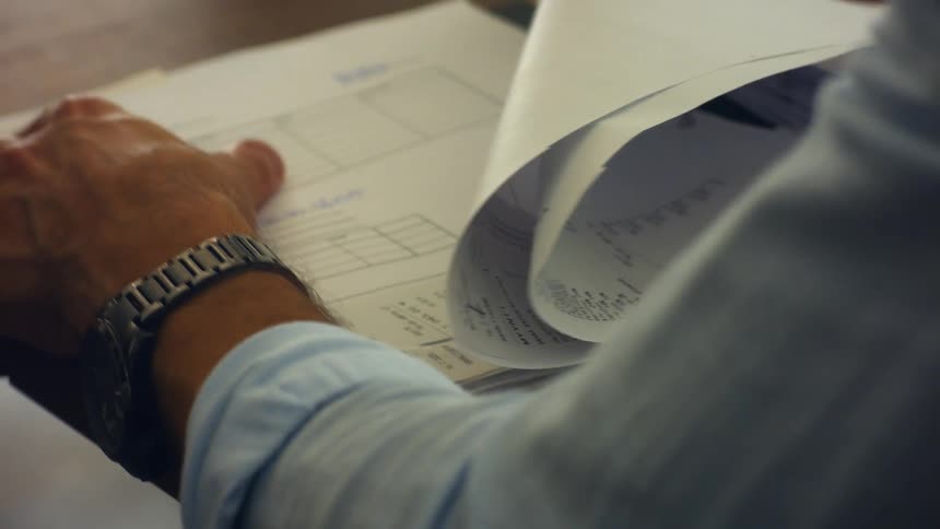 A young man sits at his desk and goes through a folder of paperwork