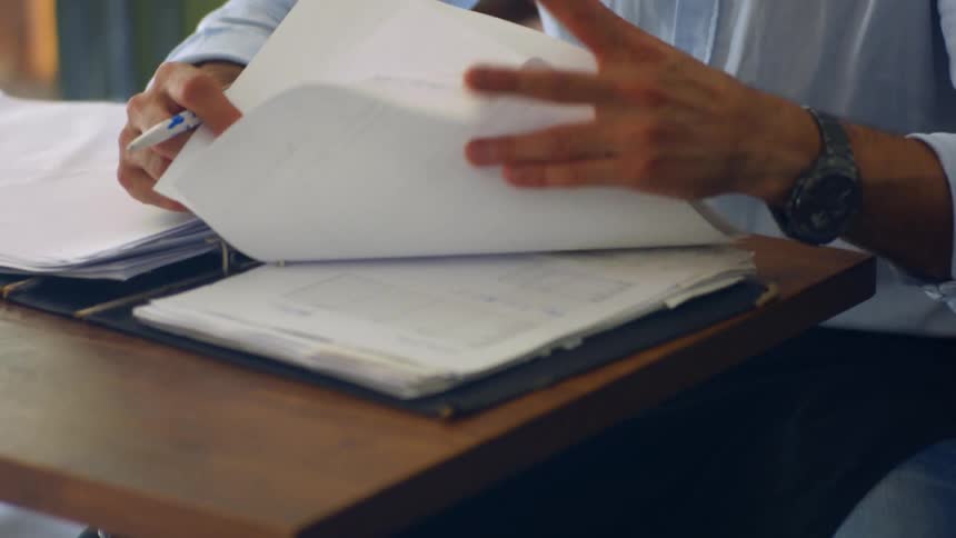 Man sitting inside at a small desk looking through tax work papers