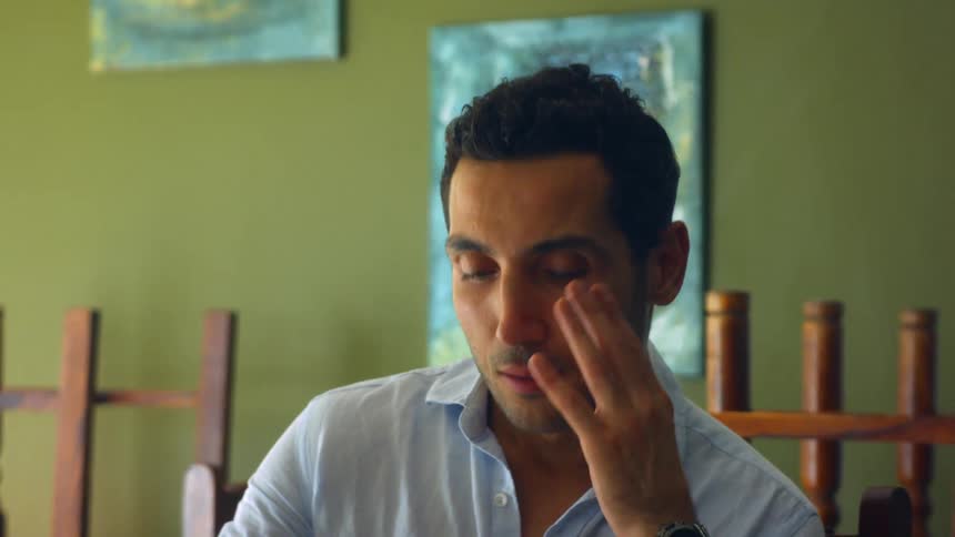 A man looks down at a piece of paper in a binder while sitting at a desk