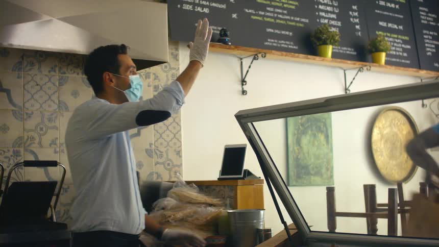 A man picks up food from a restaurant employee
