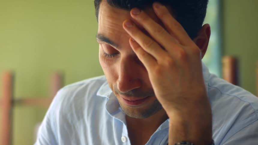 A man sits and shakes his head in frustration