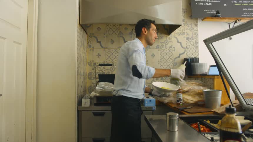 A man prepares food in a small kitchen in a restaurant
