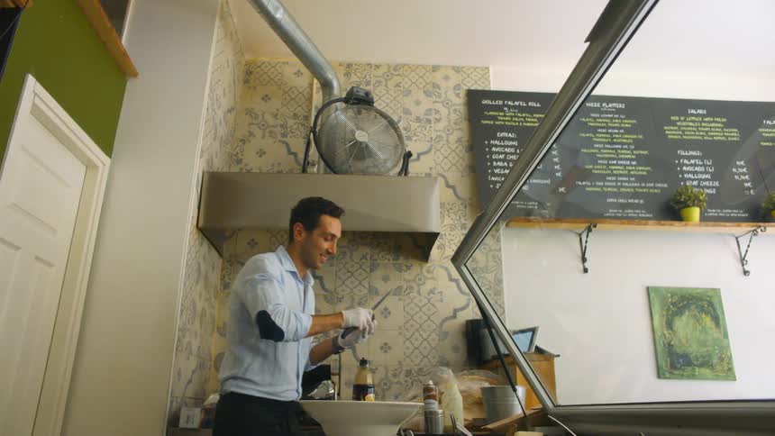 Man working behind a counter top preparing food at a food bar