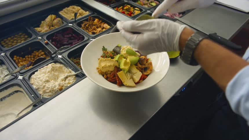 Hands preparing a dish with an avocado in a kitchen of a restaurant during the day