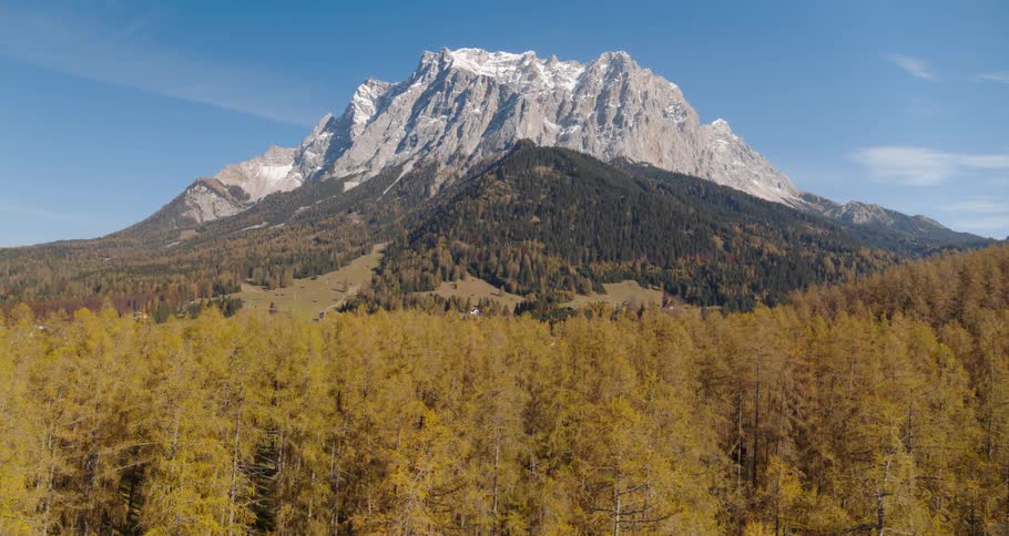 A forest with trees with a mountain range the sky and clouds in the background