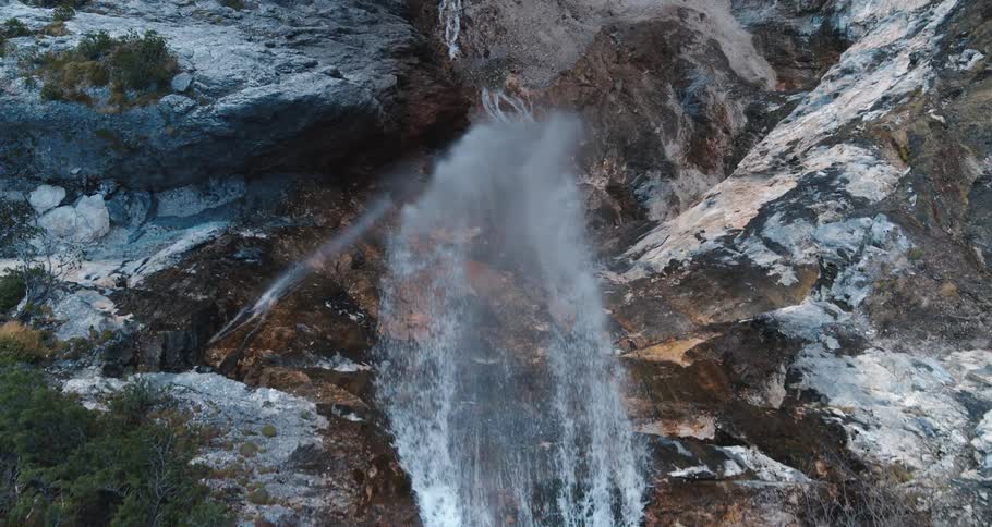 A waterfall in the mountains near rocks and cliffs