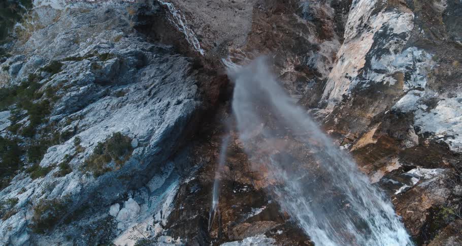 Large waterfall spilling over the edge of a tall cliff and falling to a pool below