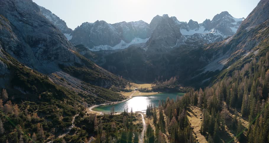 Lake occupies center of valley bordered by forest and snow covered slopes