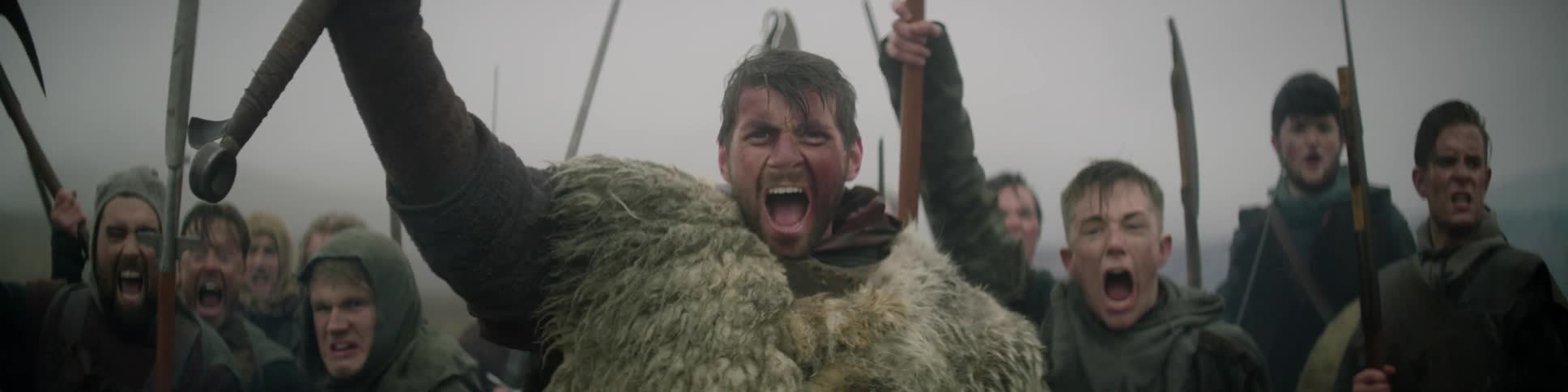 A group of men with weapons raise them in the air and yell