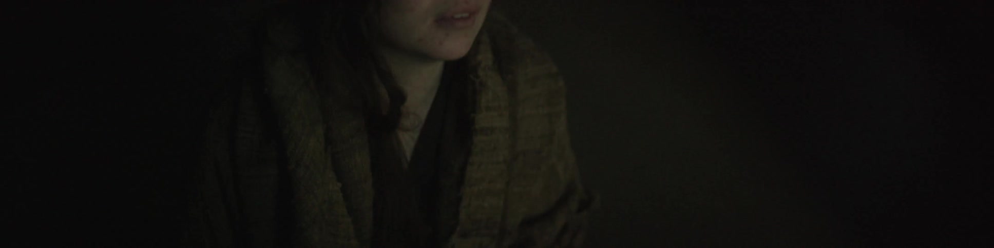 Close up of a woman wrapped in a blanket in a dark area