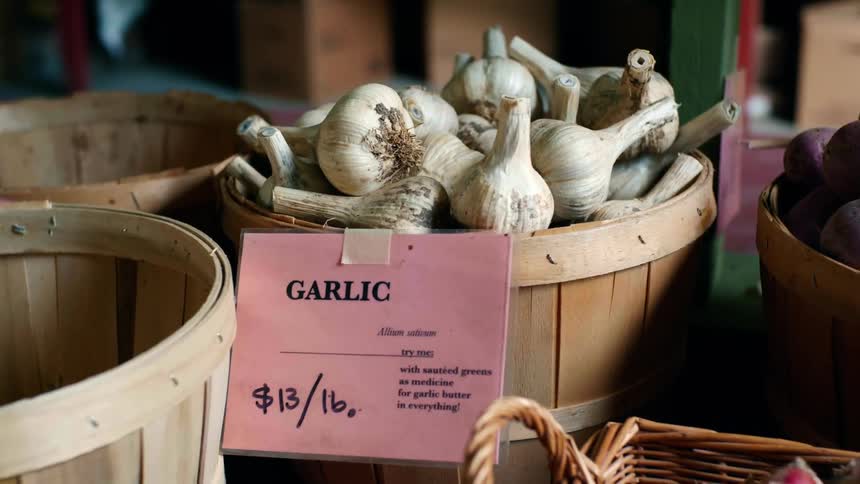 Camera pans across a basket full of garlic at a grocery store