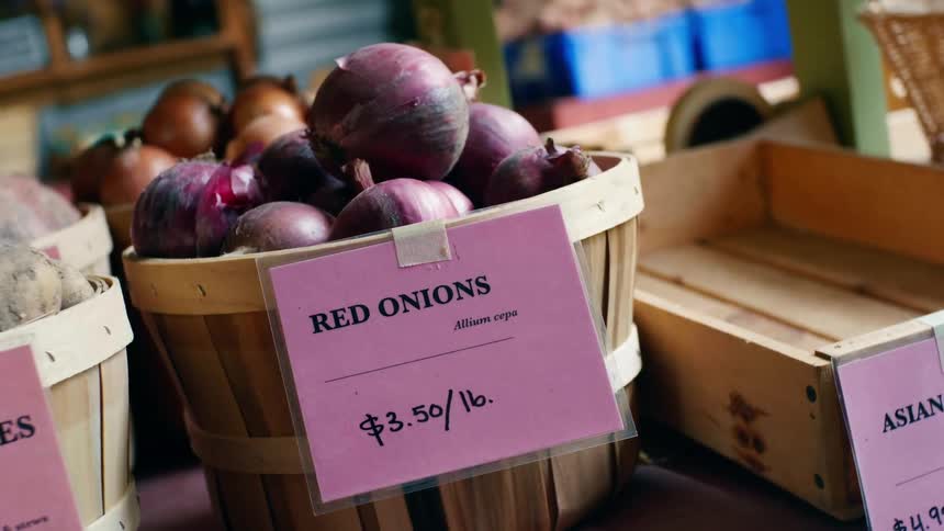 Onions and potatoes displayed in baskets with price tags for sale at a business