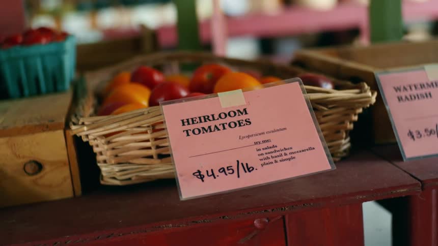 Fresh tomatoes and other produce on a wooden table in a food market
