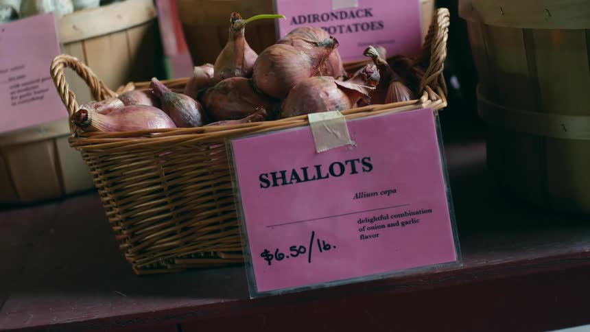 Shallots in a woven basket on a table with other fresh produce