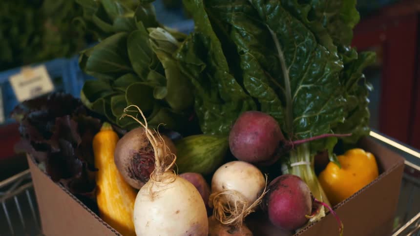 Root vegetables in a cardboard box inside of a shopping cart
