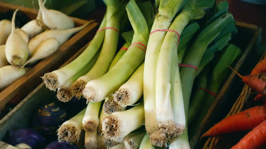 Close up of leeks carrots and other vegetables in boxes for display