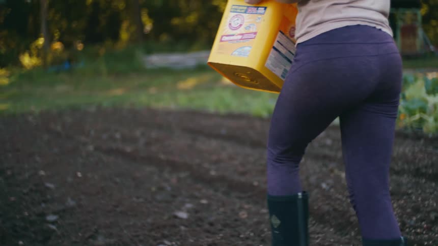A woman walks while spreading seeds in a field