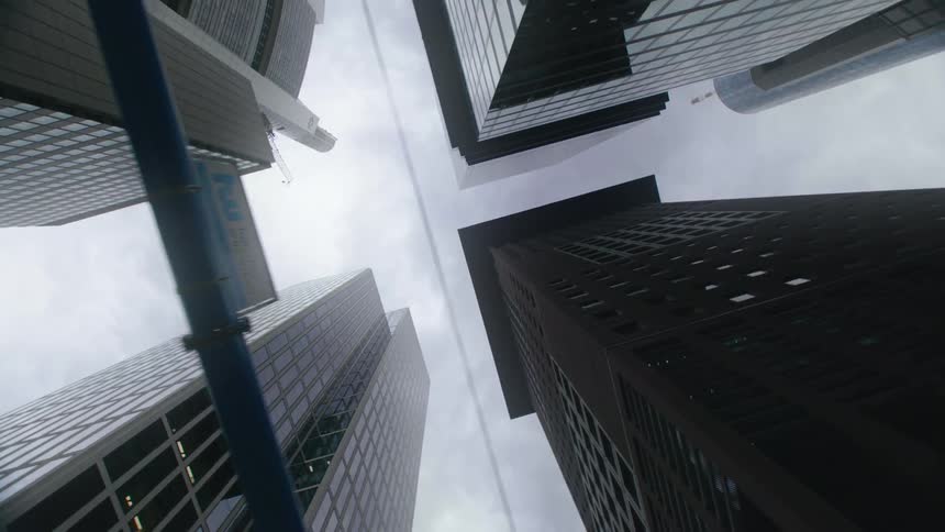 Tall sky scrapers against a cloudy blue sky being viewed from the ground up in circular movement