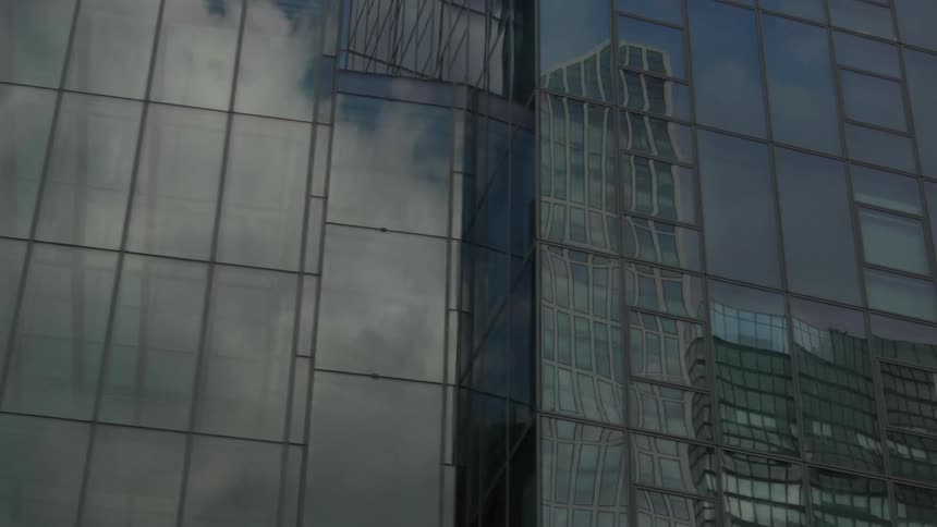 Glass on skyscrapers reflect each other and the cloudy sky